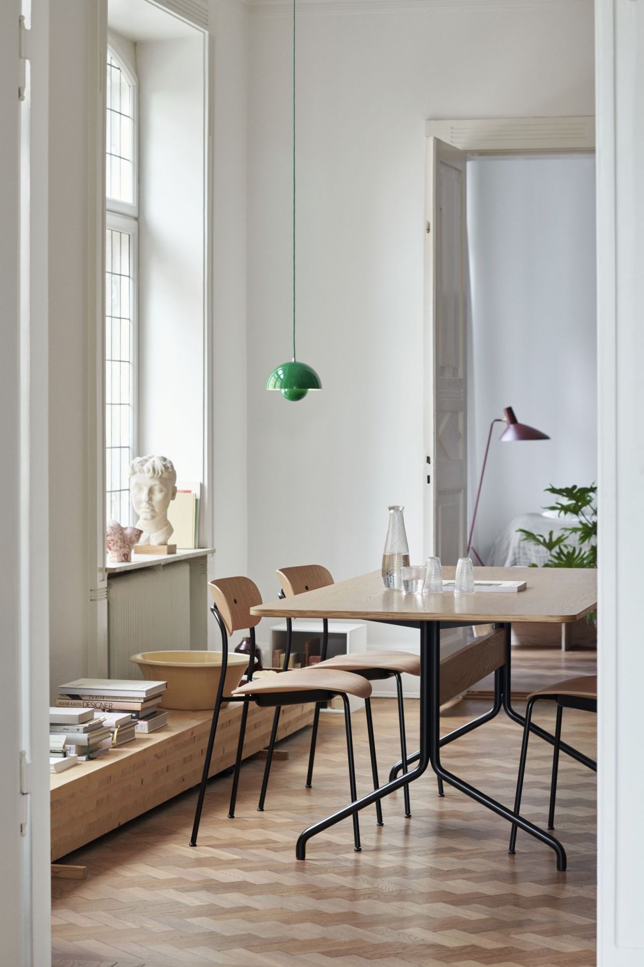 Esszimmer mit AndTradition Pavilion Tisch und Stühlen, hellem Holz, schwarzem Gestell und grüner Pendelleuchte.
