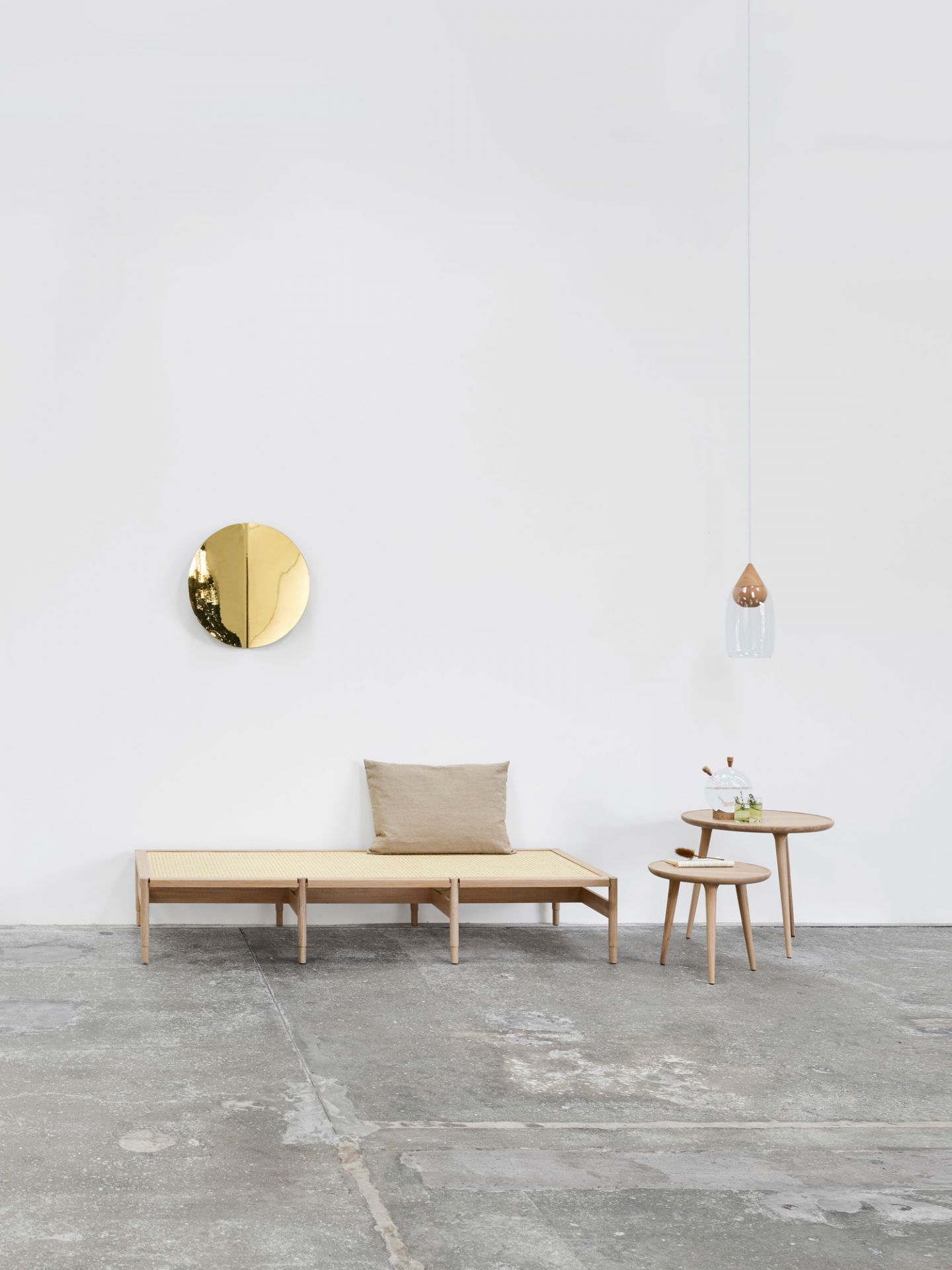 Imago Mirror Object: Runder Wandspiegel aus Messing im minimalistischen Interieur mit Holztisch und Bank.