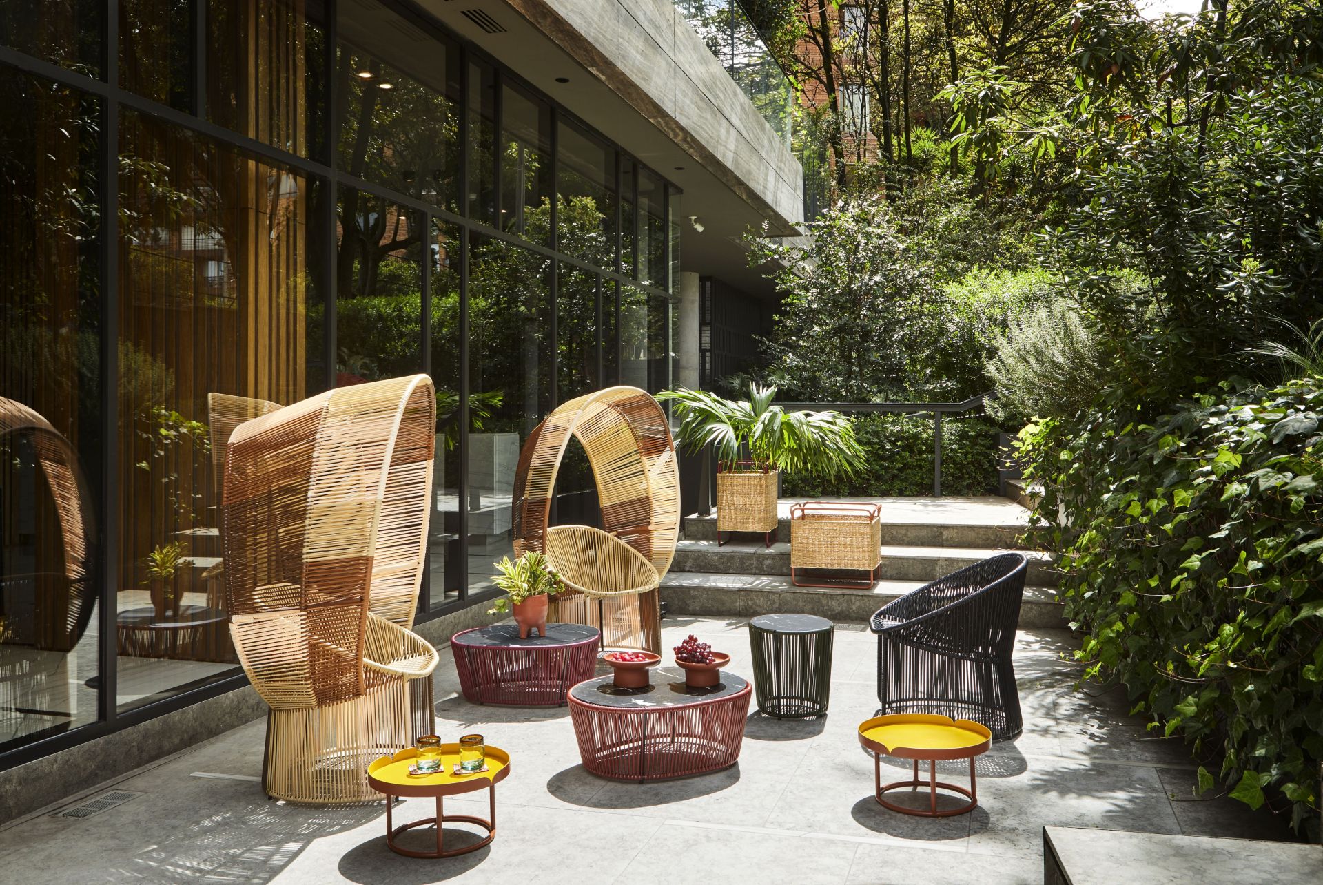 Cartagenas Reina Chair: Outdoor-Sitzgruppe mit Korbstühlen und farbigen Beistelltischen im Garten. Gartenmöbel für Terrasse.