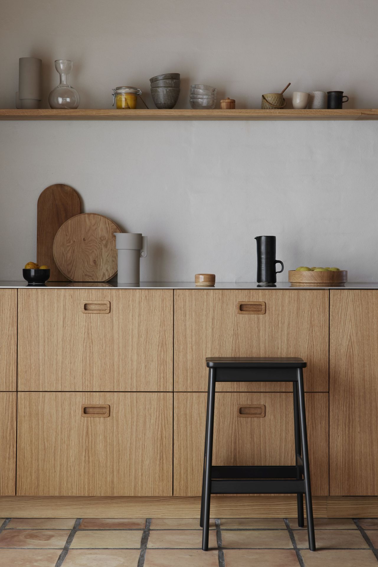 Angle Barhocker von Form & Refine in Schwarz vor einer modernen Küche mit Holzfronten.