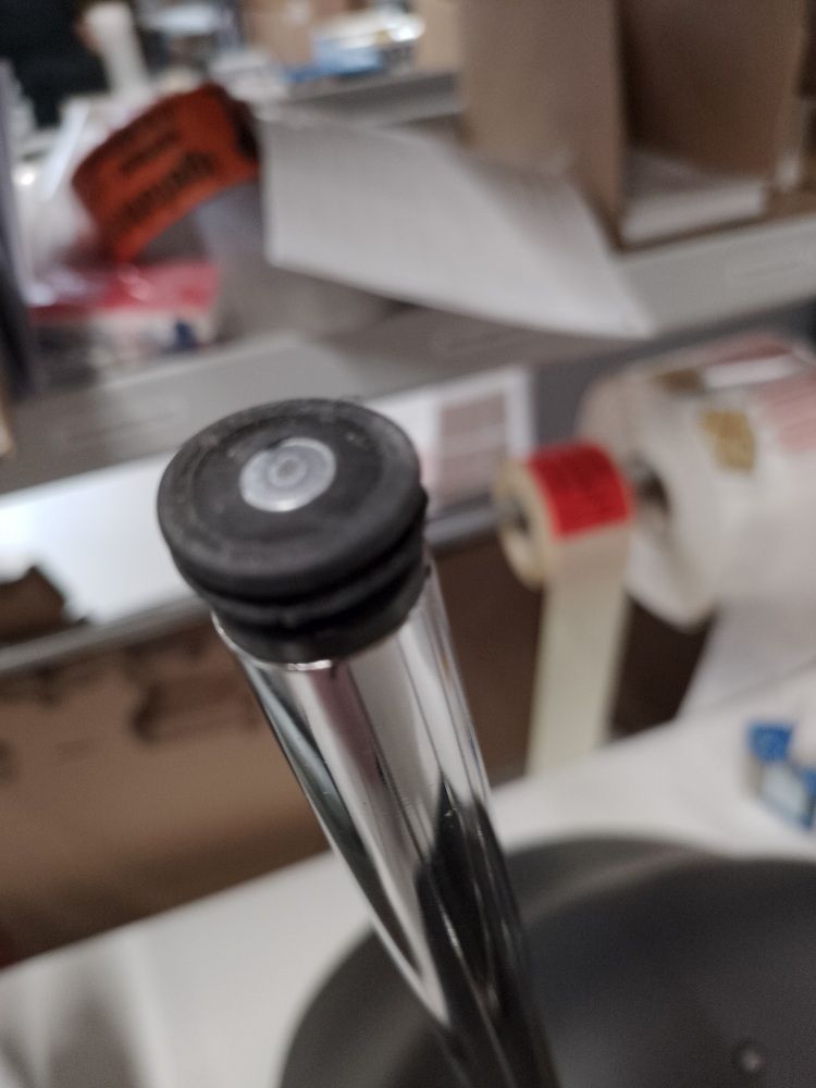 Detailaufnahme vom Fuß eines schwarzen About A Chair AAC26 Stuhls mit Chromgestell, Mängelexemplar.