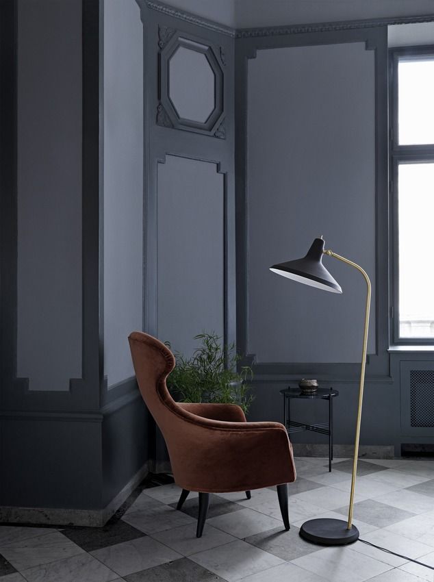 Gubi Stehleuchte G-10 in Schwarz und Gold neben Sessel in stilvollem Interieur.