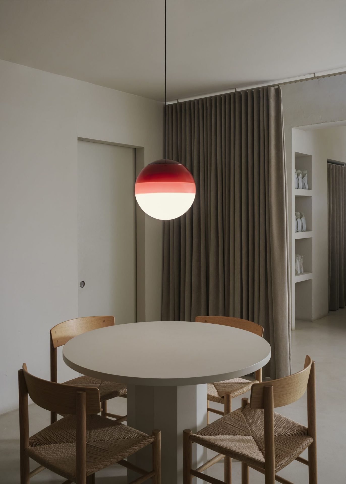 Dipping Light Pendelleuchte von Marset in Rot-Weiß über Esstisch mit Stühlen.