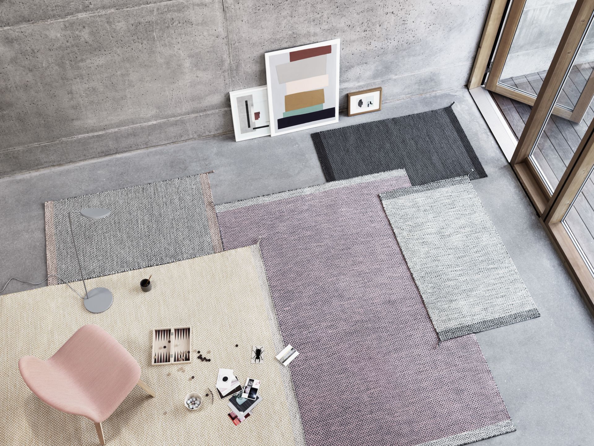 Ansicht von oben: Rosa Muuto Visu Lounge Chair Stuhl auf beigem Teppich mit Spielbrett.