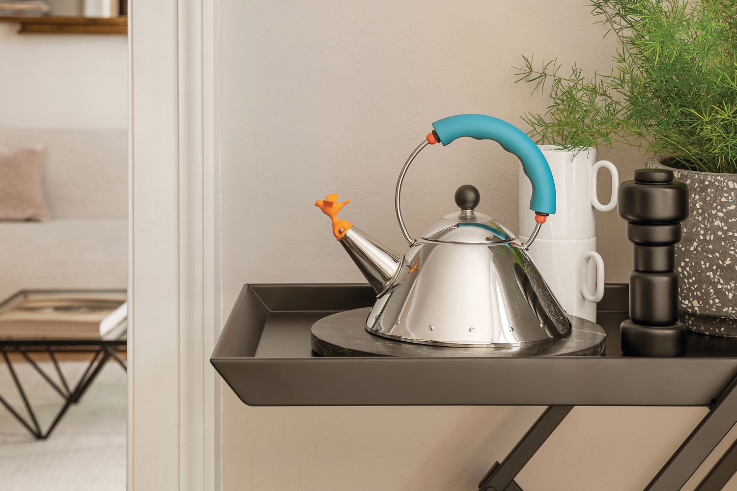 Alessi Wasserkessel mit Vogelpfeife, Edelstahl, blauem Griff auf einem Servierwagen. Design-Klassiker für die Küche.