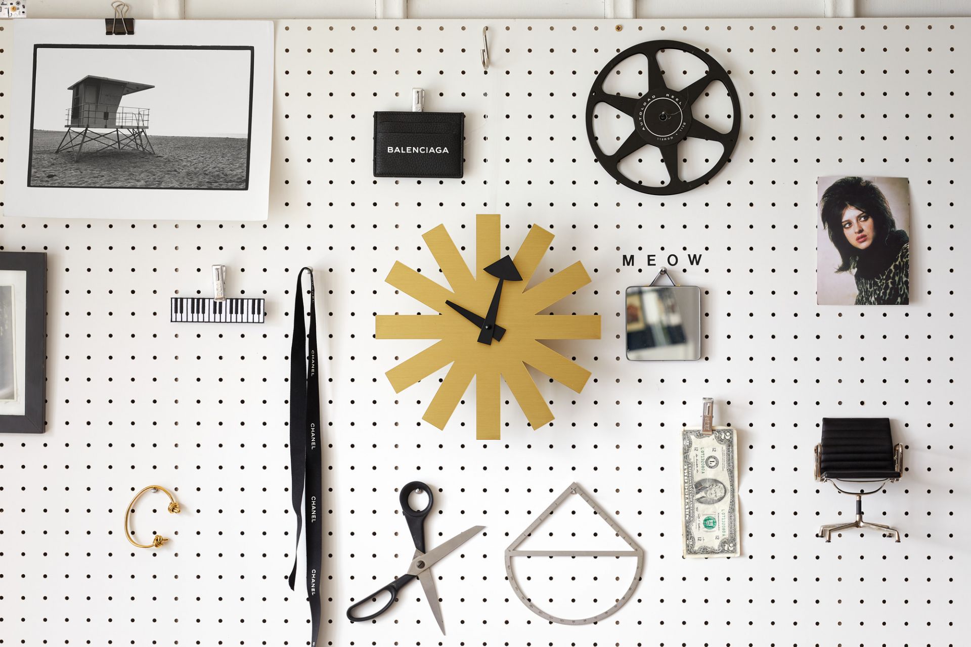 Goldene Asterisk Wanduhr von Vitra an einer Lochwand, modernes Design für Wohnzimmer und Büro.