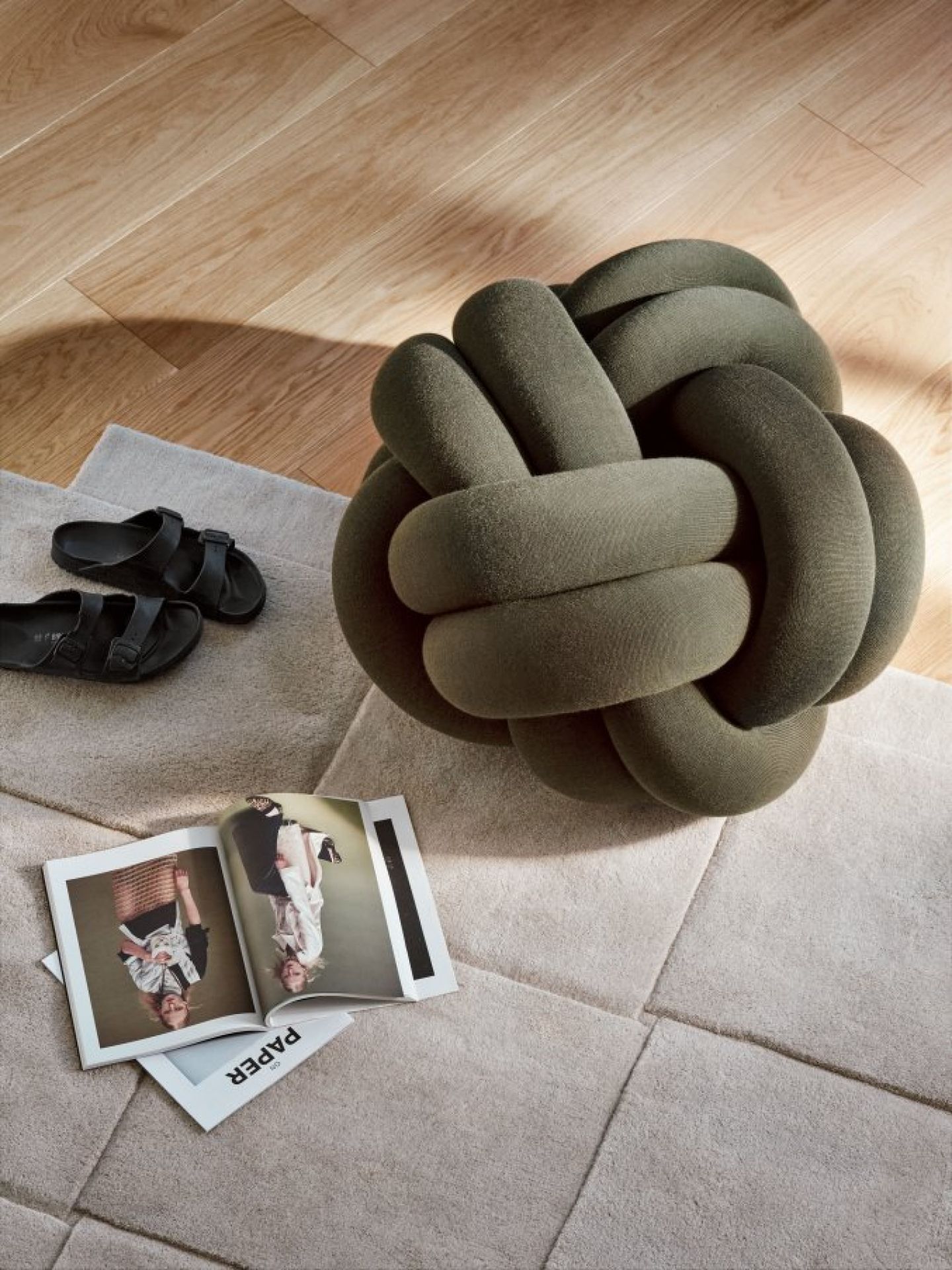 Nahaufnahme: Grünes Knot Kissen von Design House Stockholm auf beigem Teppich.