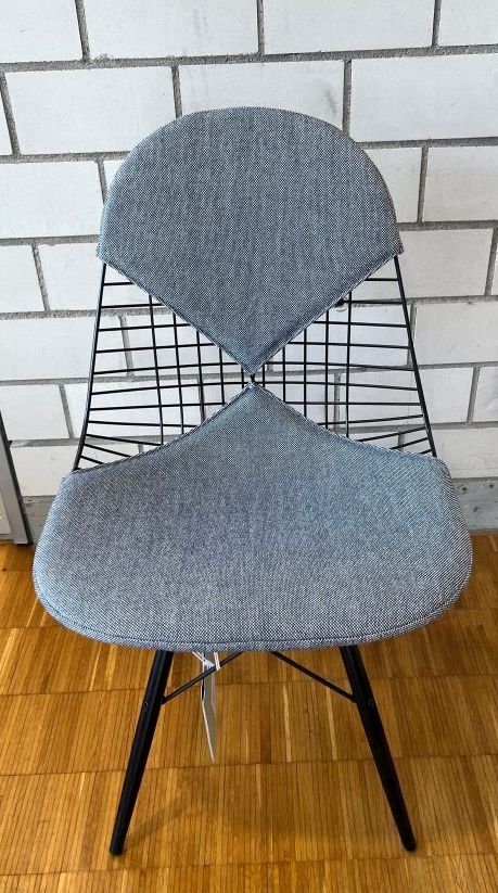 DKW Wire Chair Stuhl mit blau-elfenbeinfarbener Polsterung, schwarzem Drahtgestell und schwarzen Beinen.