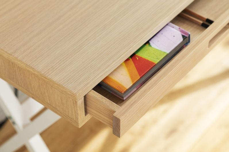 Detailaufnahme des Hyppolite Sekretär Hartô aus Eiche mit offener Schublade und bunten Büchern.