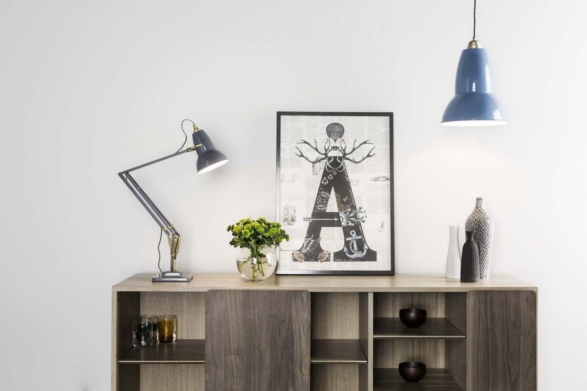Graue Original 1227 Anglepoise Tischleuchte aus Messing auf einem Sideboard mit Dekoration und Lampe.