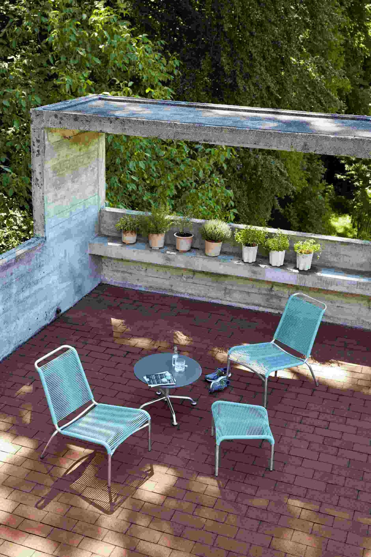 Altorfer Lounge Stuhl Outdoor Embru: Zwei blaue Lounge Stühle und Hocker auf einer Terrasse.