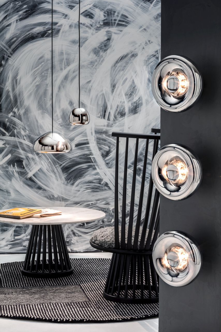 Nahaufnahme von drei silbernen Tom Dixon Void Surface LED-Wandleuchten an einer dunklen Wand.