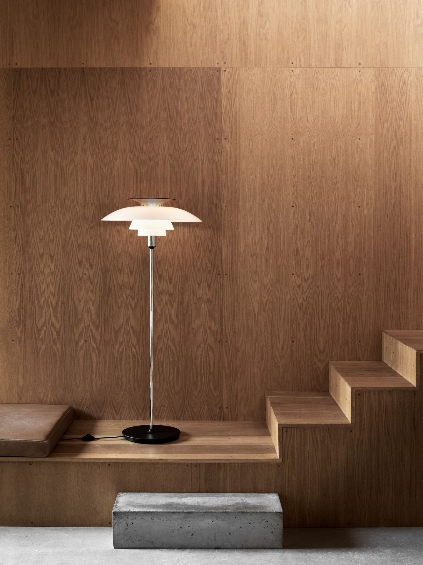 PH 80 Stehleuchte von Louis Poulsen: Elegante, weiße Designerlampe mit Chromfuß vor Holzwand.