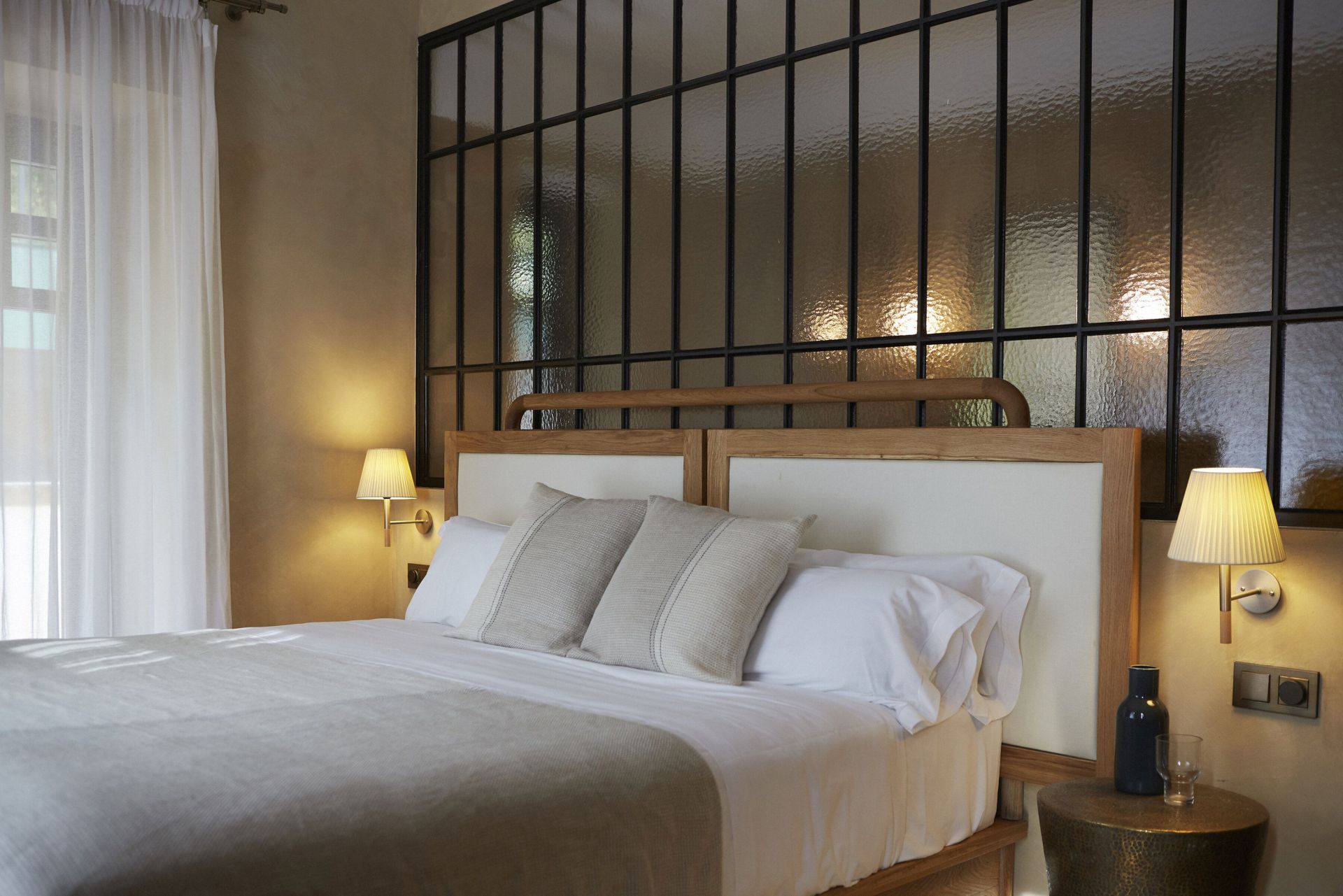 Schlafzimmer mit Bett und zwei BC2 Wandleuchten von Santa & Cole für stimmungsvolle Beleuchtung.