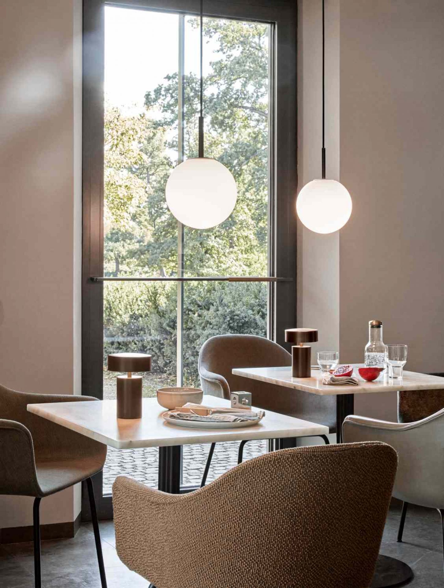 Zwei Audo TR Bulb Pendelleuchten mit Opalglas über Tischen in einem Restaurant.