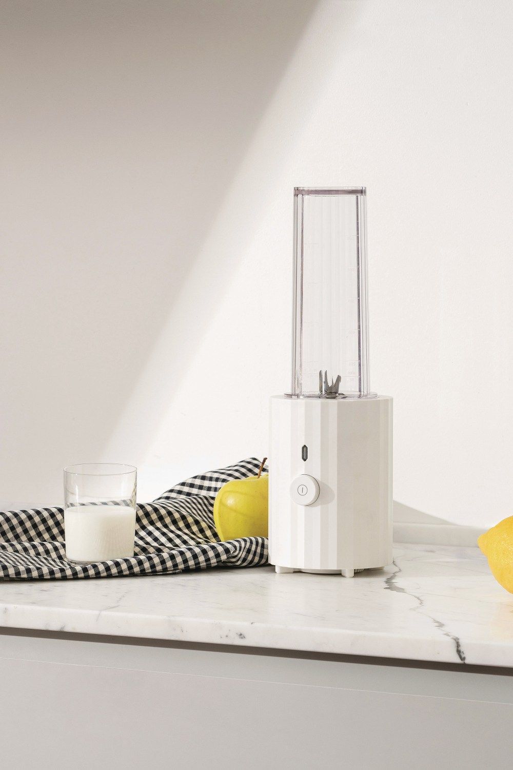 Weißer Alessi Plissé Smoothie Maker auf Marmor, mit Milch, Apfel und Zitrone.