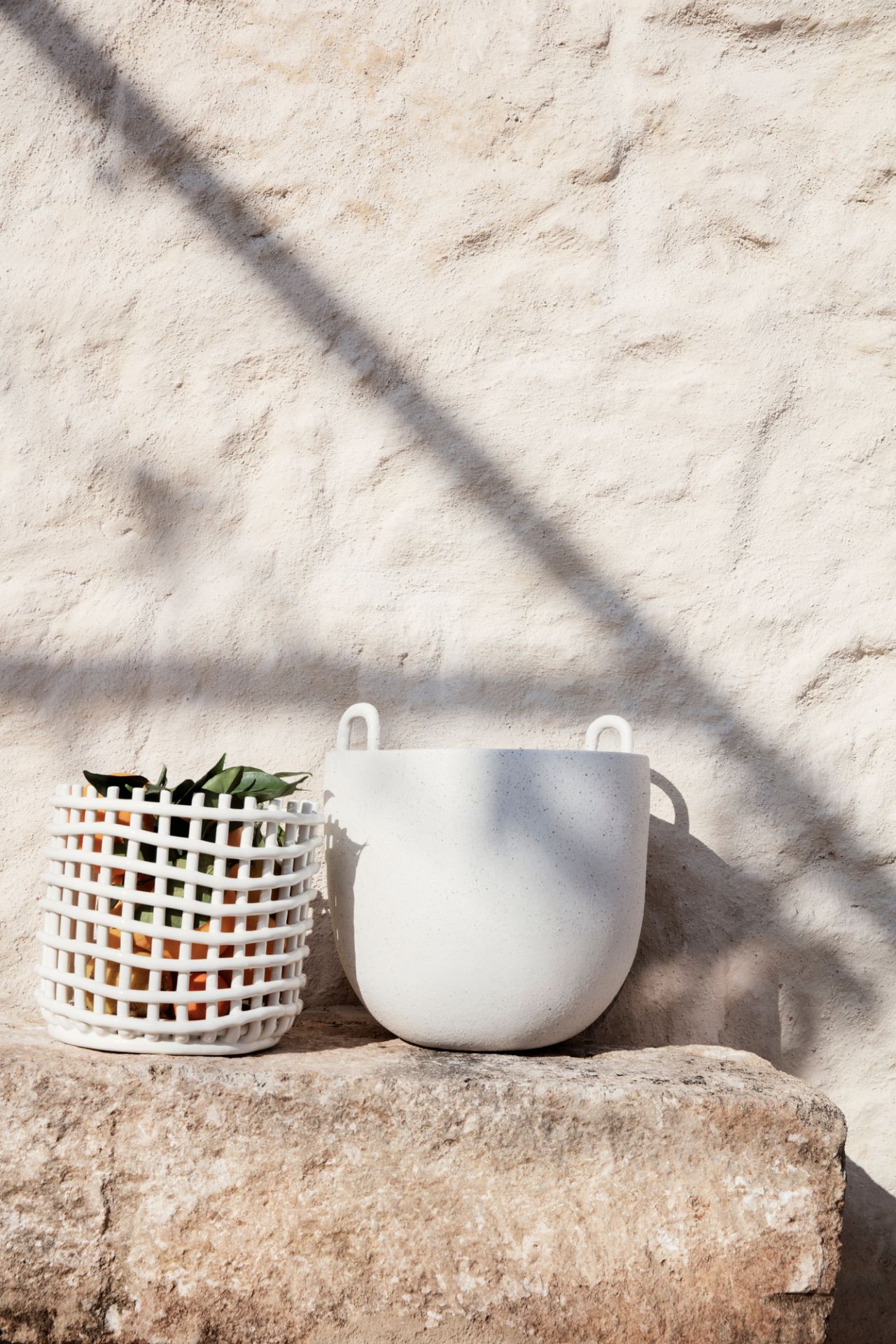 Großer, weißer Keramik Korb von Ferm Living, einer gefüllt mit Orangen, auf Stein.