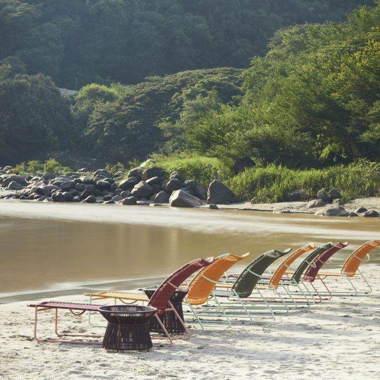 Cielo Daybed Outdoor Liege in Rot und Pink am Strand mit Tisch und Hocker.
