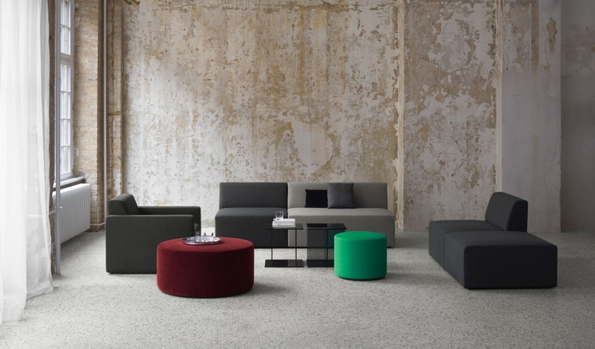 SF06 Kerman Modulsofa von e15 in modernem Design mit Sesseln und farbigen Hockern.