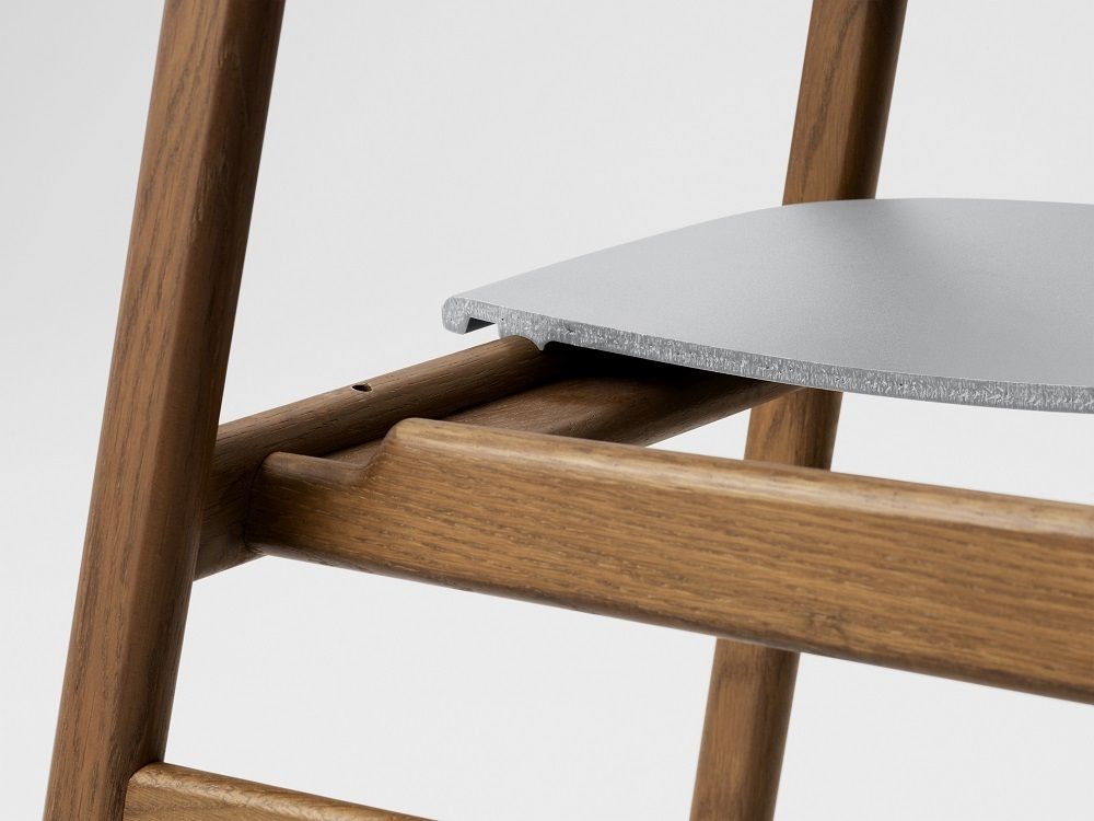 Detailaufnahme vom Herit Chair Stuhl von Normann Copenhagen: Holzrahmen und graue Sitzfläche im minimalistischen Design.