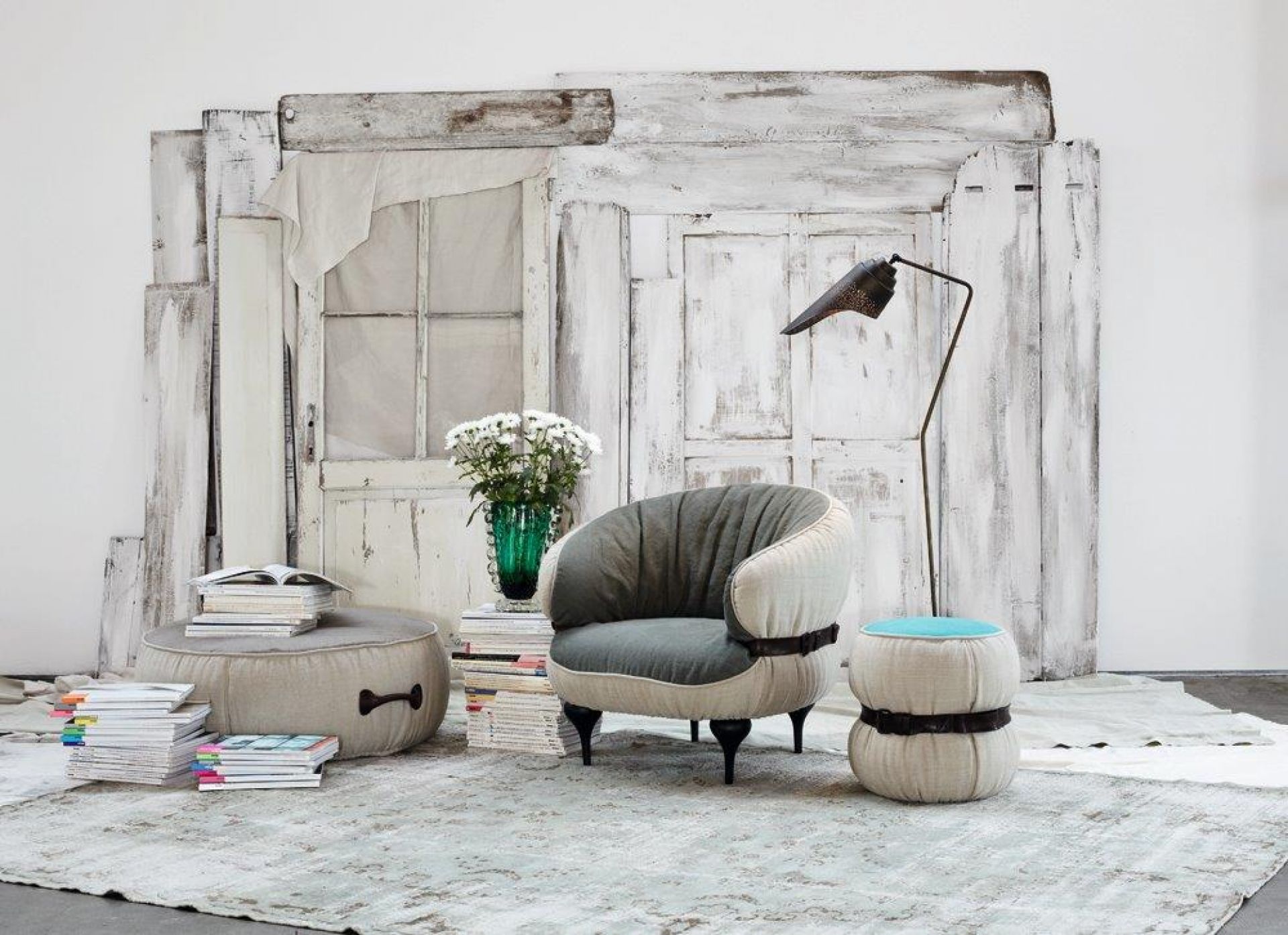 Gemütliche Sitzecke mit Moroso Diesel Chubby Hocker, Sessel und Stehleuchte vor rustikalem Hintergrund.