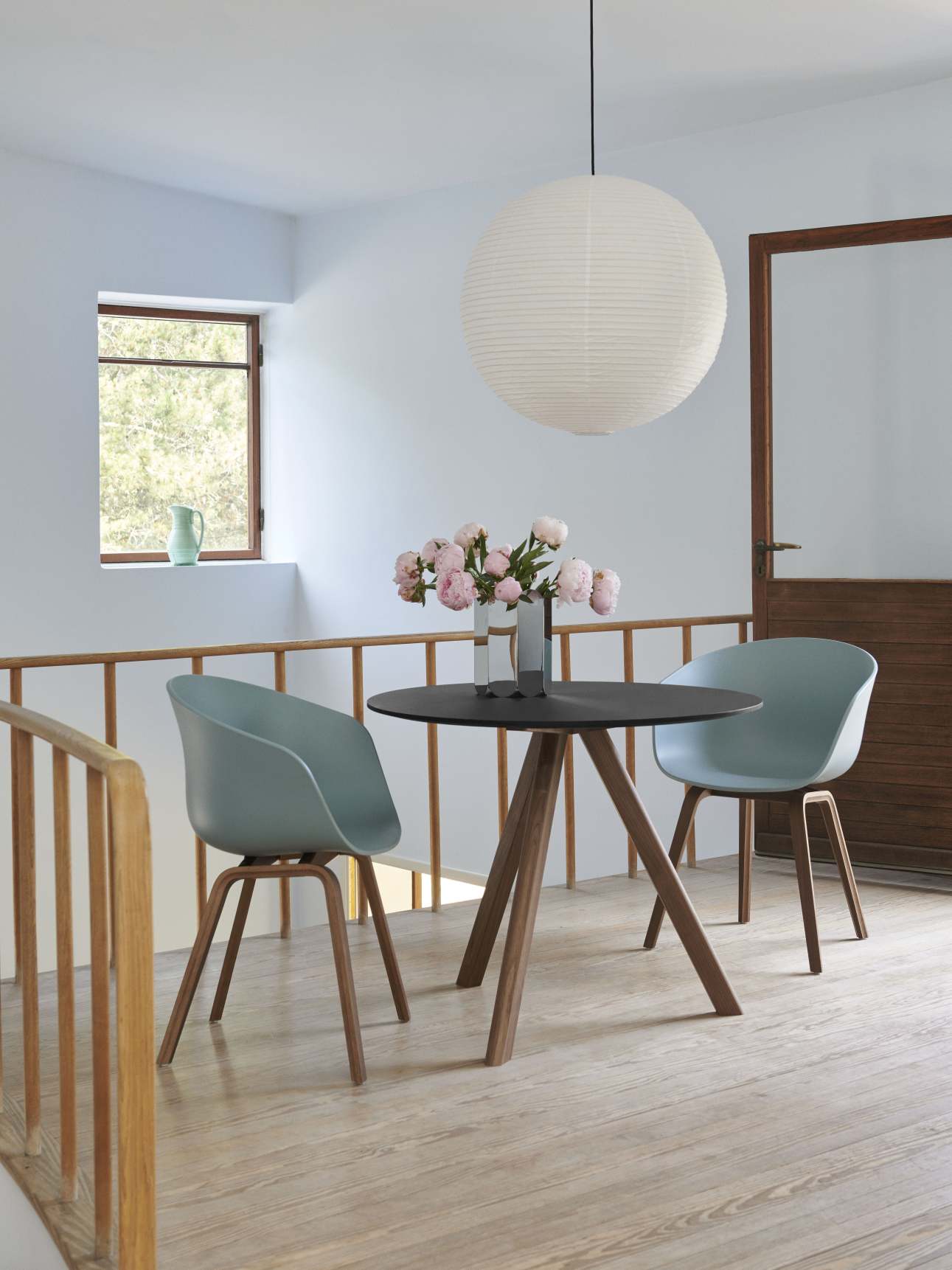 About A Chair AAC22 Stuhl in Azure Blue mit Eiche-Gestell an schwarzem Tisch.