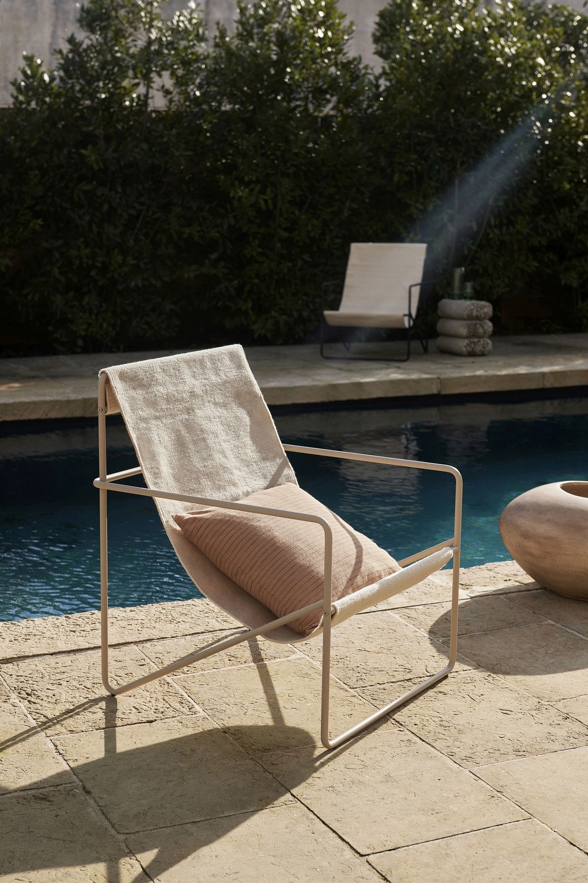Ferm Living Desert Chair Loungesessel in Beige am Pool mit Kissen und modernem Design.