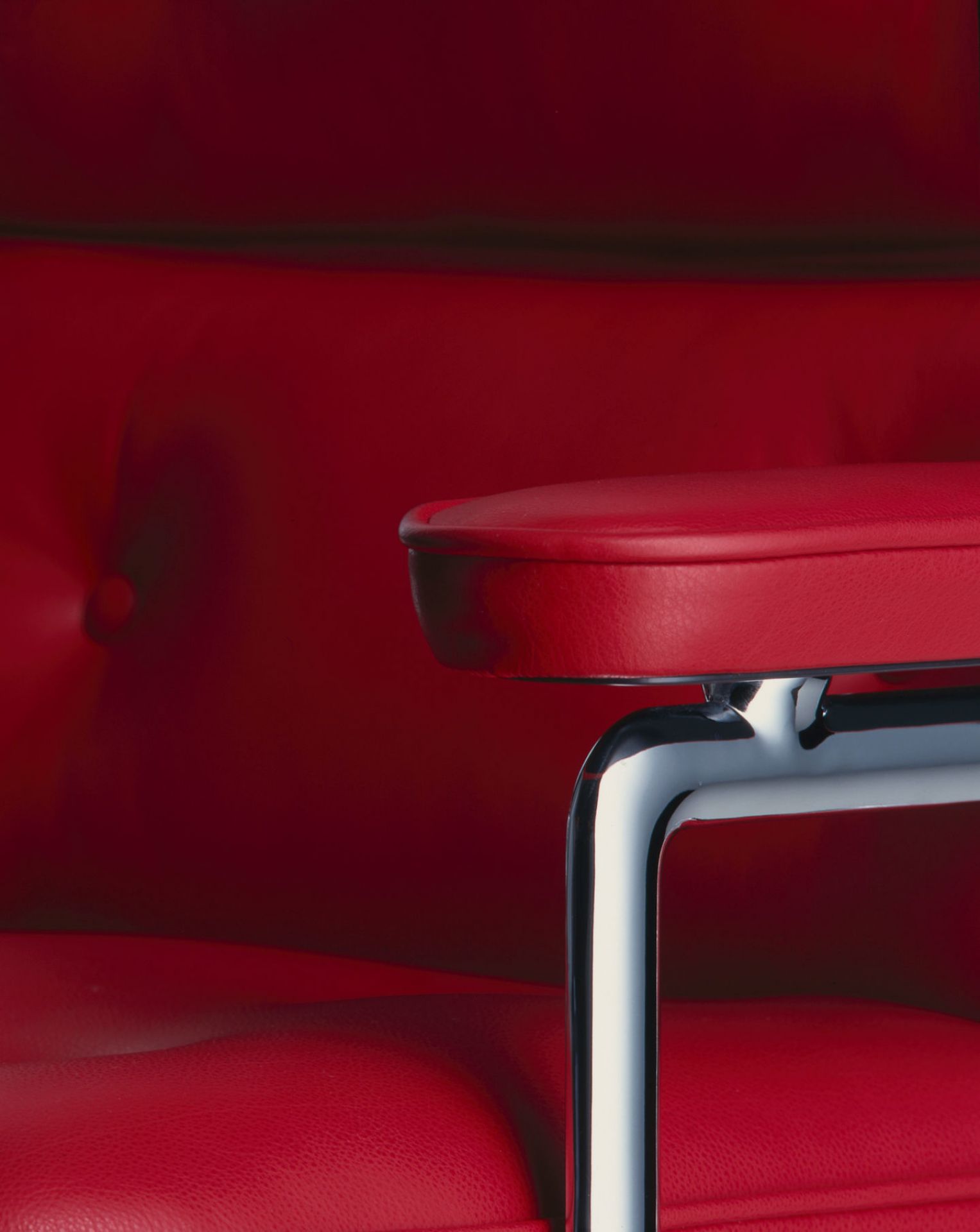 Detailaufnahme des roten Vitra Lobby Chair ES104 mit verchromtem Armlehnen-Gestell.