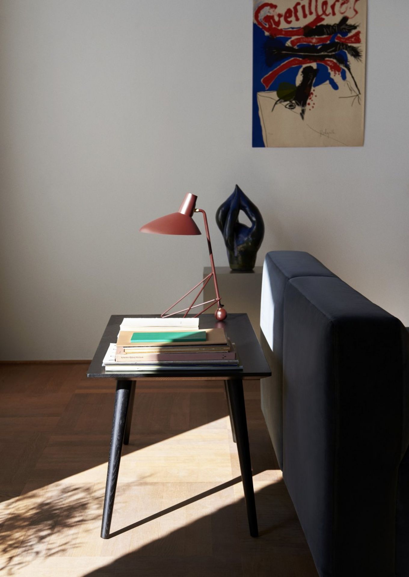 Schwarzer In Between Table Couchtisch von AndTradition mit Lampe und Büchern im Wohnzimmer.