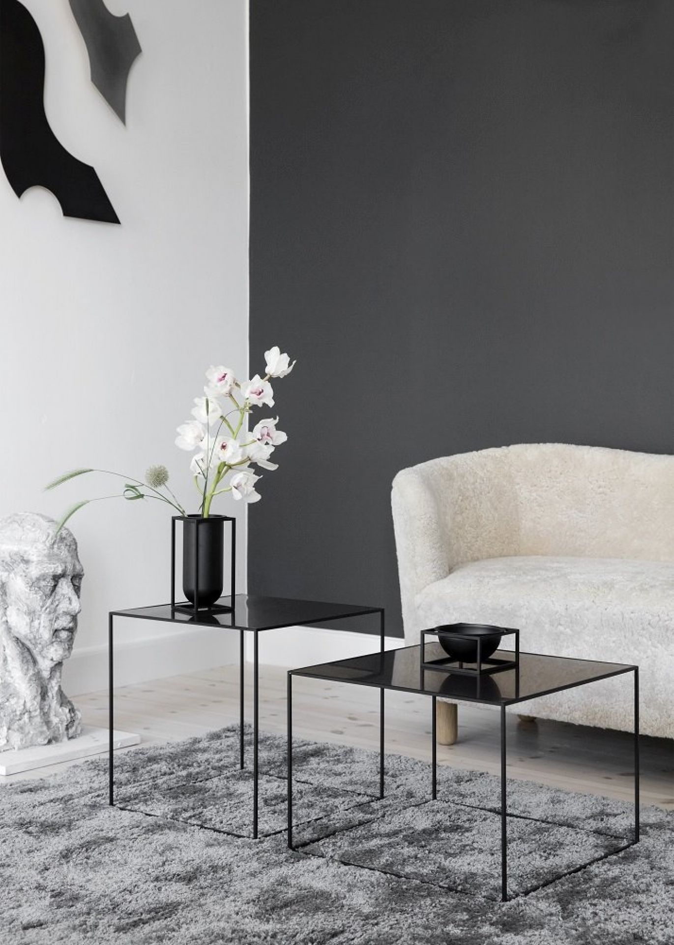 Helles Wohnzimmer mit Audo Mingle Sofa, schwarzen Couchtischen, Blumenvase und grauer Teppich für gemütliches Wohnen.