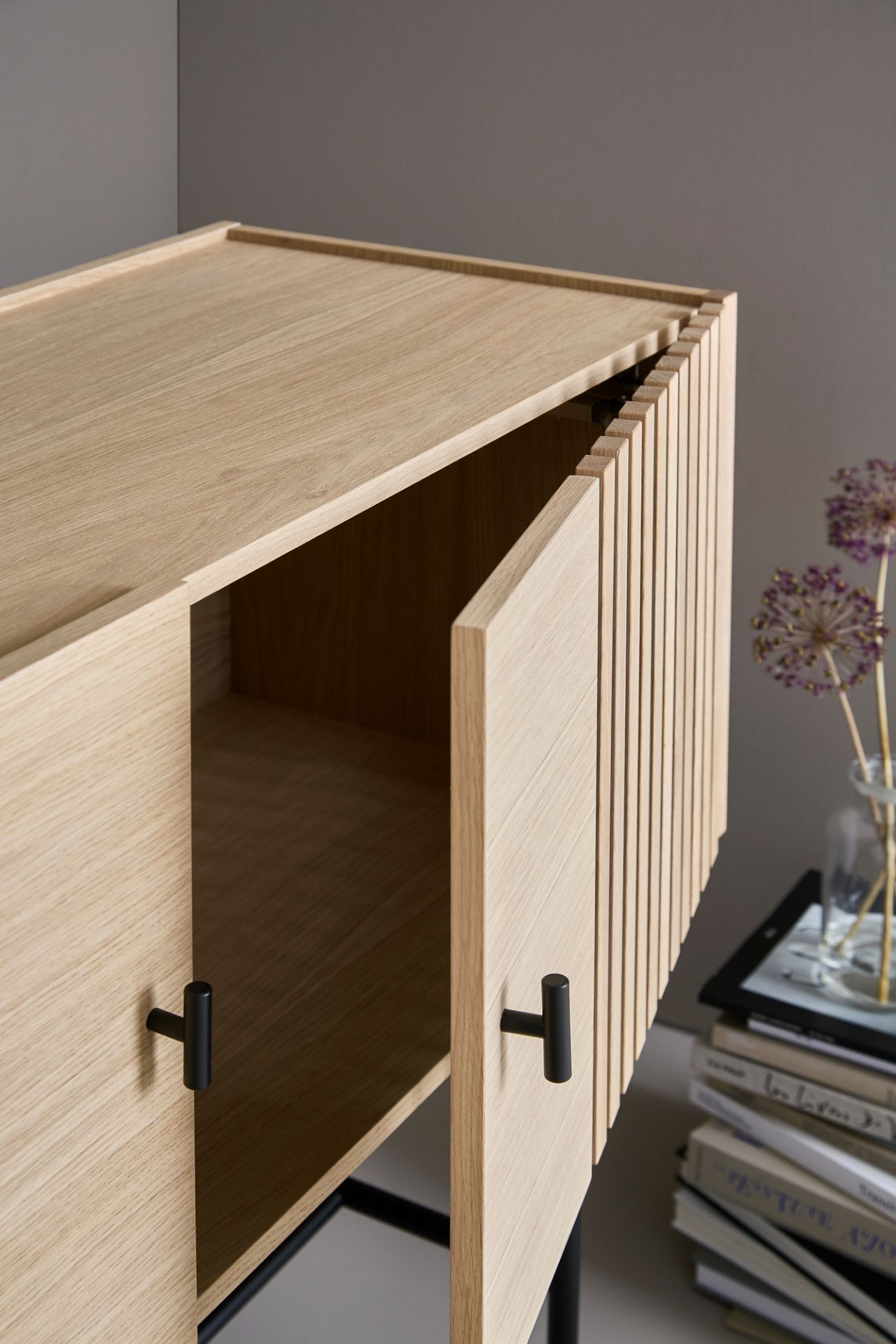 Detailaufnahme: Array Sideboard von Woud, 120cm, helle Holzoptik, schwarze Griffe, offene Tür.