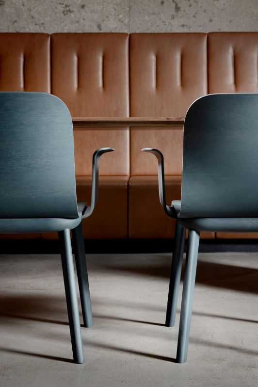 Zwei Aeon Comfort Armlehnstühle in blau vor einer braunen Sitzbank und Tisch.