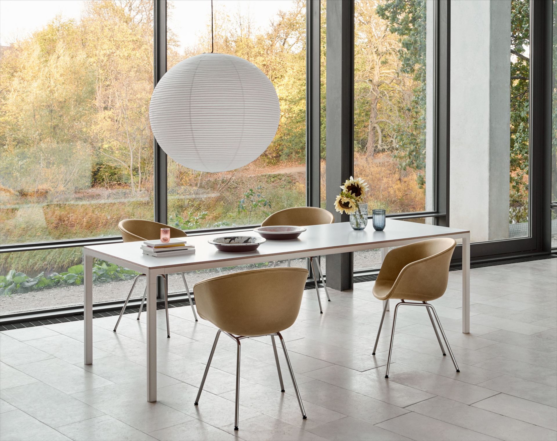 Esszimmer mit HAY About A Chair AAC27 Stühlen in Beige, weißem Tisch und großer Fensterfront.