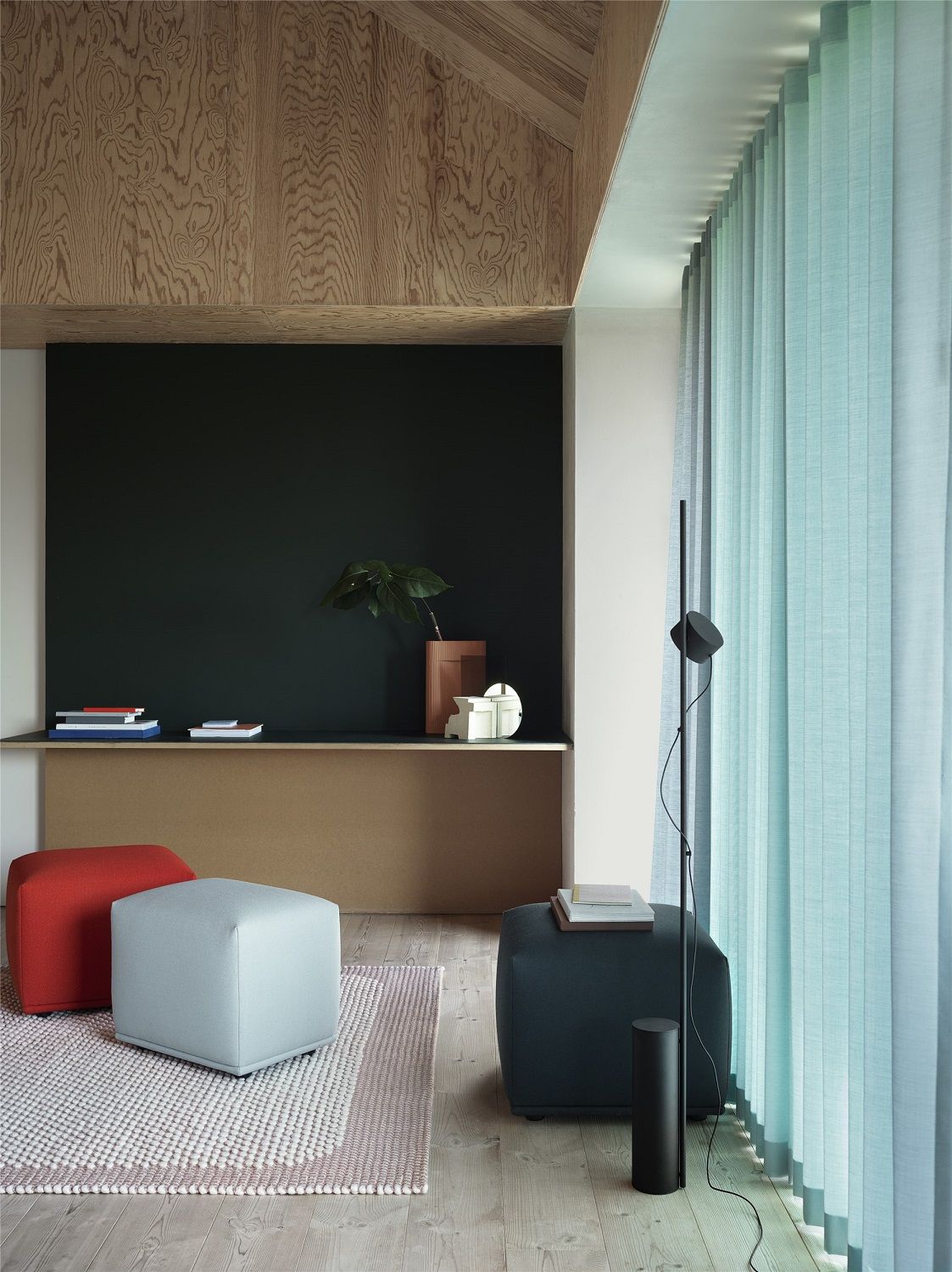Wohnzimmer Interieur mit rotem, blauem und grauem Echo Pouf Hocker von Muuto auf einem Teppich.