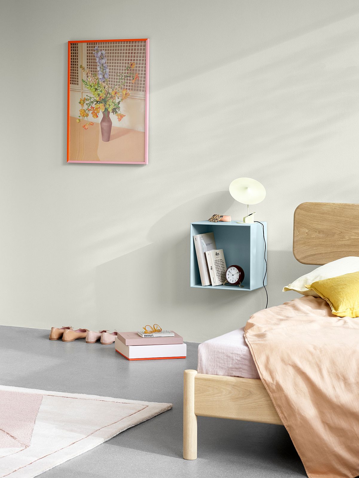 Helles Schlafzimmer mit blauem Montana Mini Modul als Nachttisch, Lampe, Buch und Uhr.