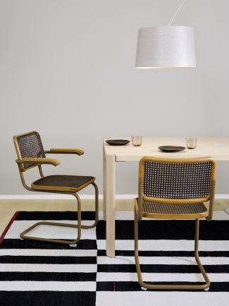 S 64 V Thonet Freischwinger Stühle aus Stahlrohr mit Wiener Geflecht an Esstisch auf Schwarz-Weiß-Teppich.
