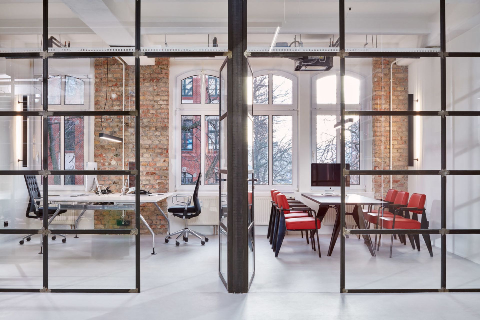 Modernes Büro mit Vitra Fauteuil Direction Sessel in Rot und Schwarz an einem Konferenztisch.