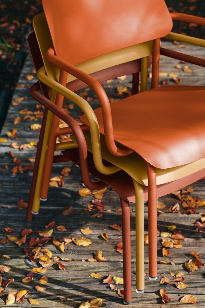Drei Fermob Studie Lounge Sessel Outdoor in Herbstfarben gestapelt auf einer Holzterrasse mit Laub.