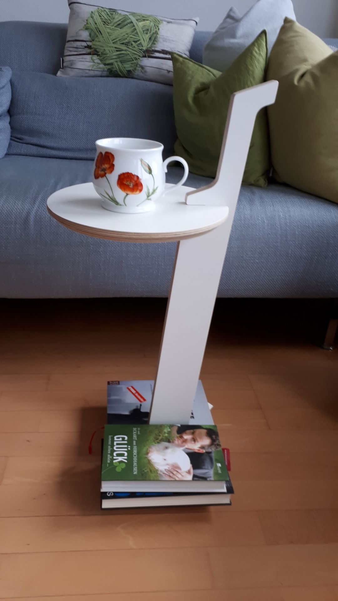 Lesestelle Bücherregal to go: Weißer Beistelltisch mit Ablagefläche und Bücherstapel als Basis, Tasse darauf.
