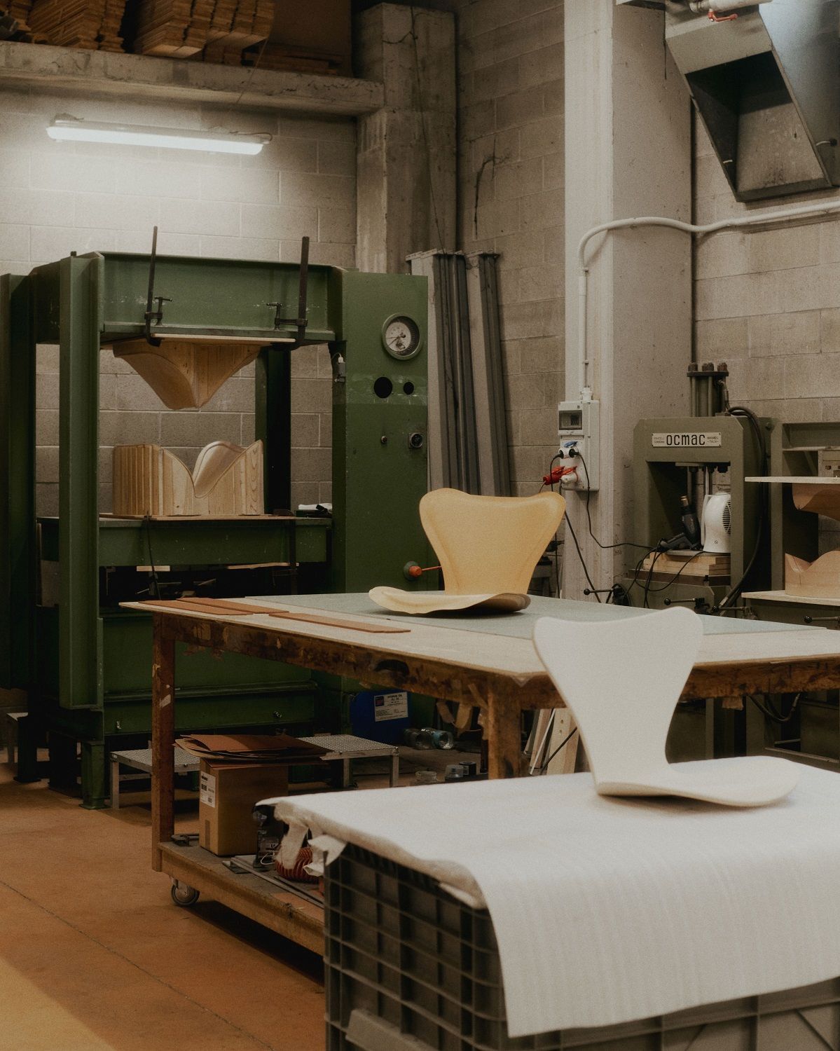 Siebener Stuhl von Fritz Hansen in der Produktion: Unlackierte Sitzschalen auf Werkbank und Produktionsmaschinen.