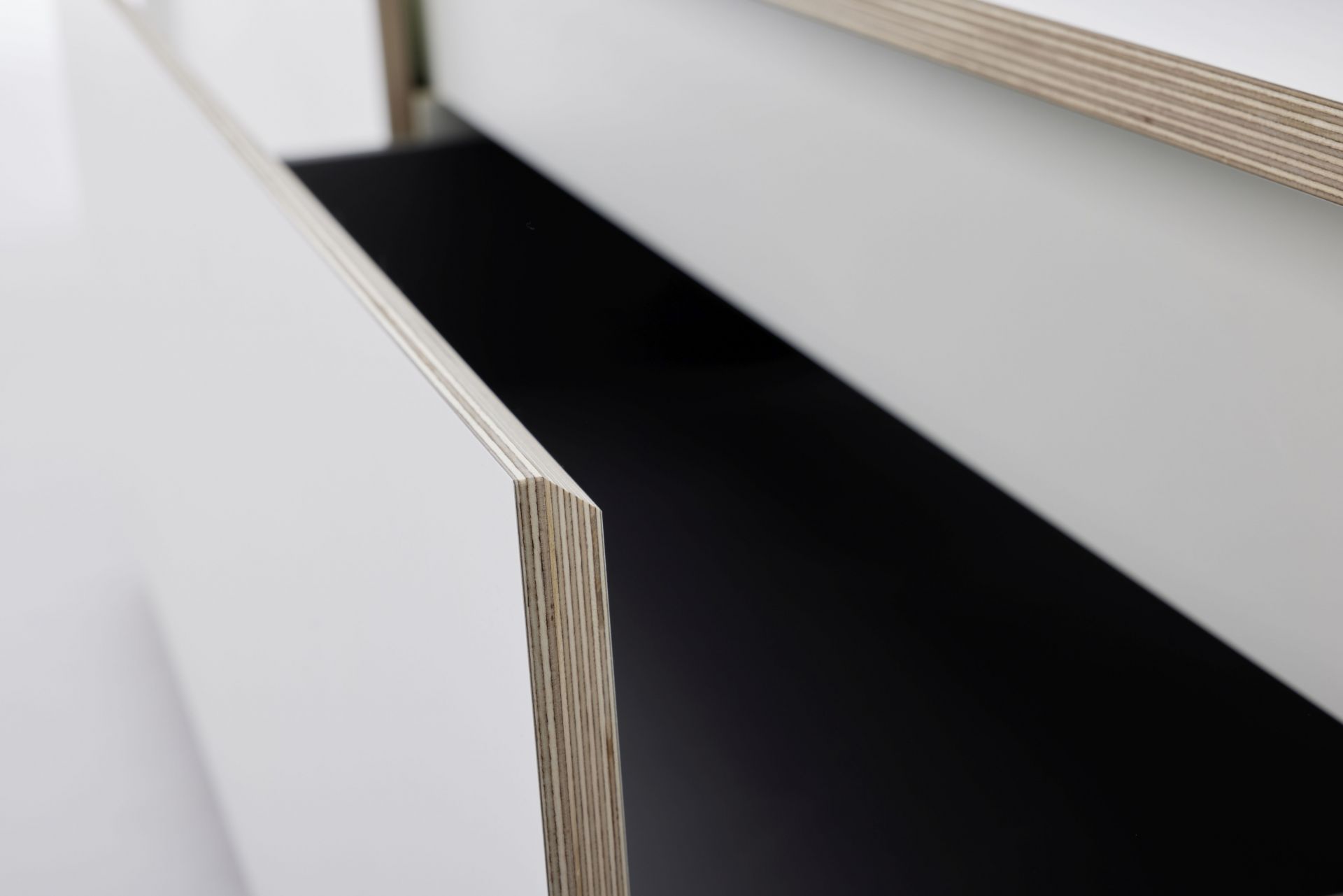 Detailaufnahme eines weißen Spaze Bettes von Müller Möbelwerkstätten mit offenem Schubladenelement aus hellem Holz.