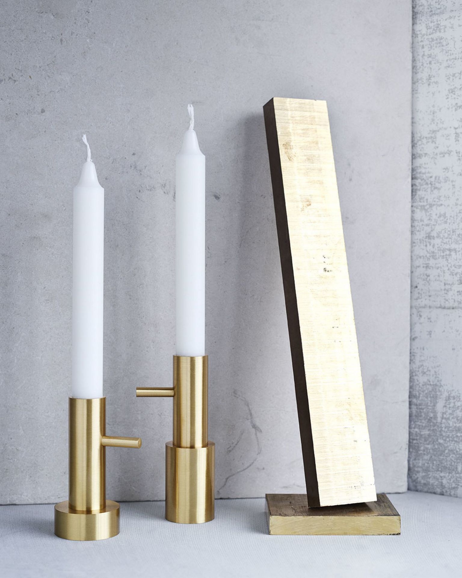 Zwei goldene Kerzenhalter mit weißen Kerzen und ein goldener Dekogegenstand. Fritz Hansen Kerzenständer.