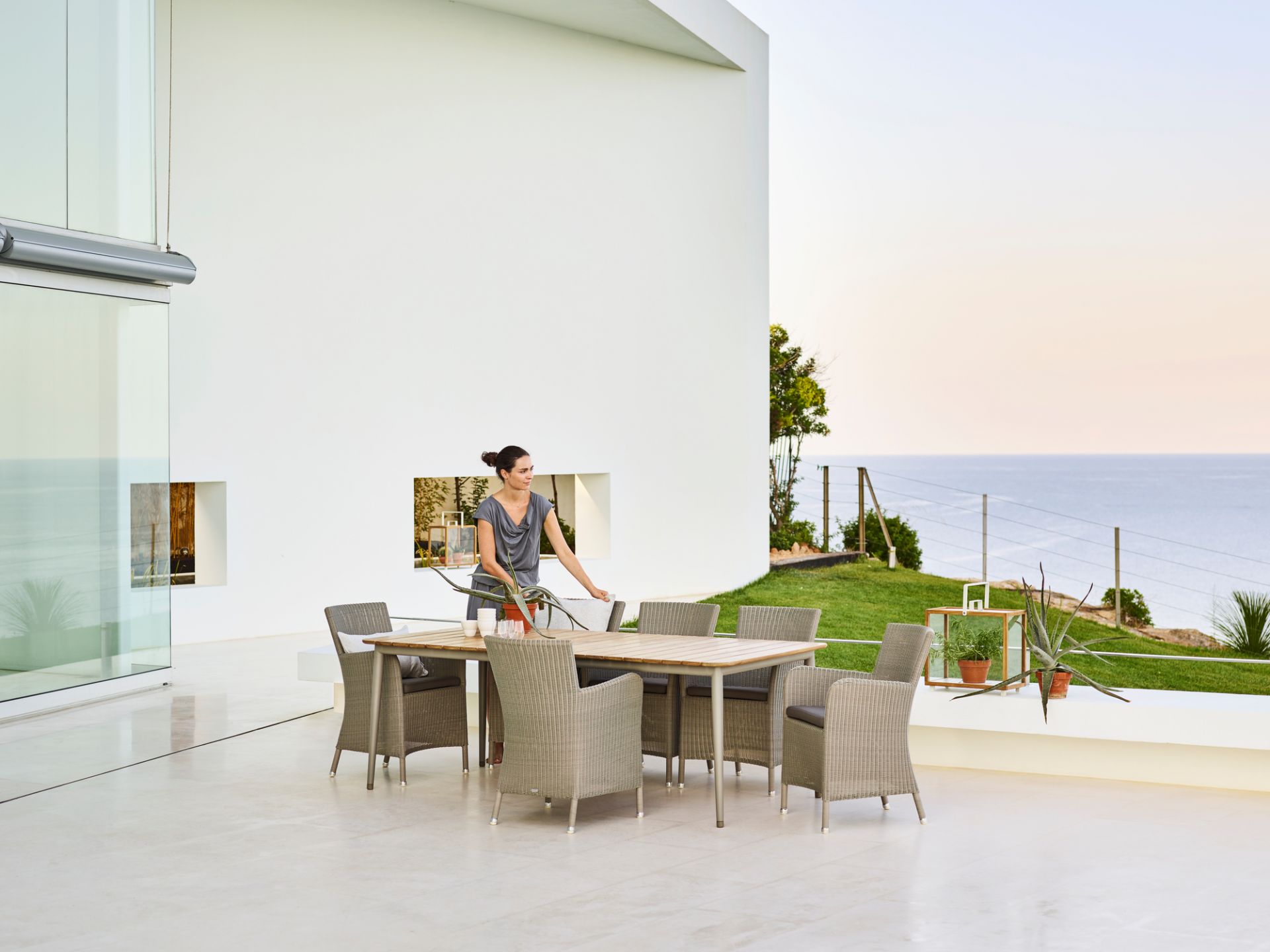 Cane-Line Hampsted Outdoor Sessel und Esstisch-Set auf einer Terrasse mit Meerblick.