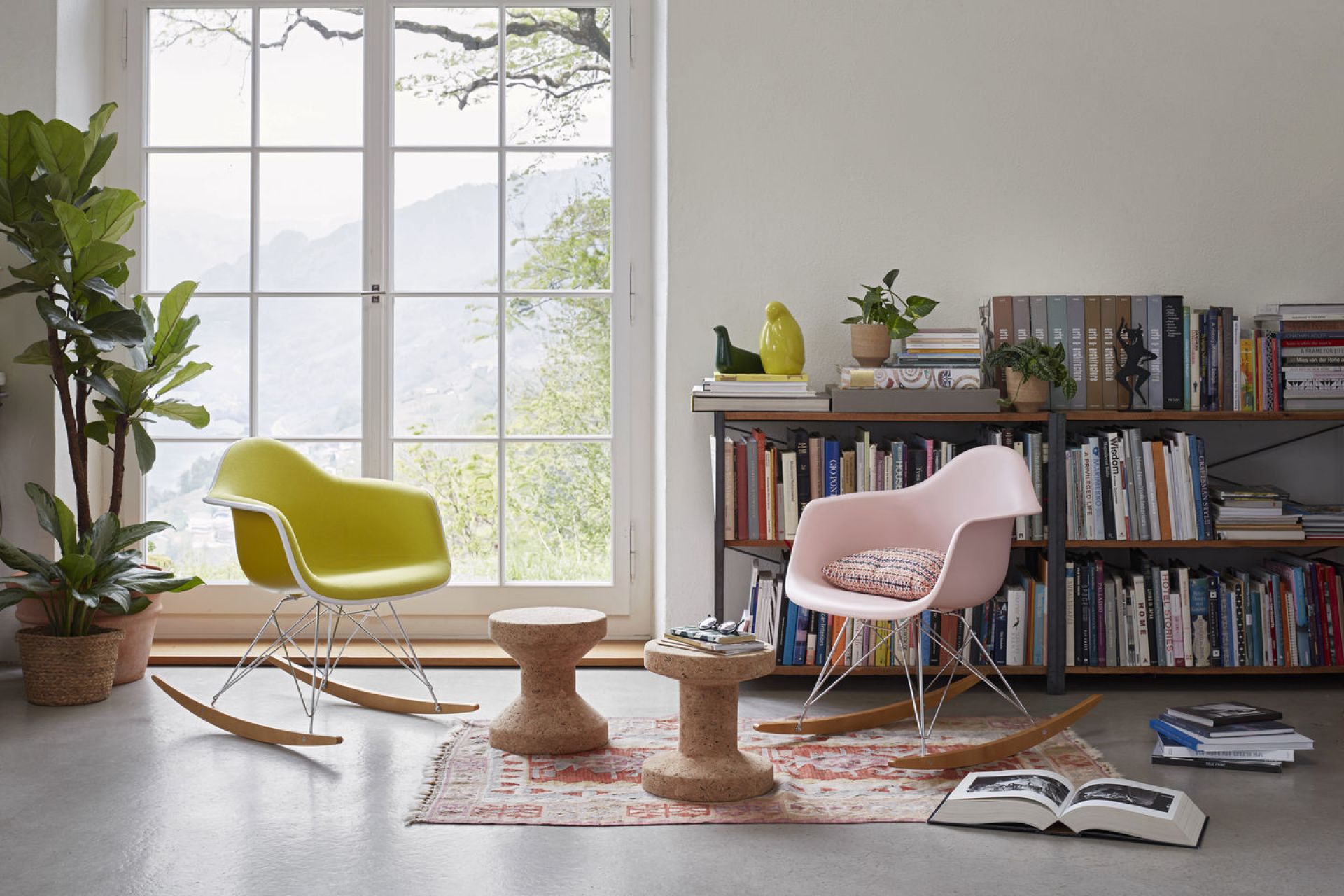Vitra Eames RAR Schaukelstühle in Gelb und Rosa vor Fenster und Bücherregal. Designklassiker.
