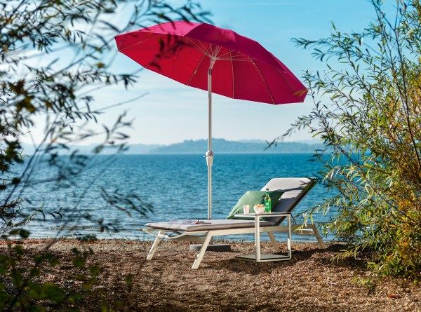 Weishäupl Pagodenschirm in Pink mit Liegestuhl und Beistelltisch am Seeufer für entspannte Stunden im Freien.