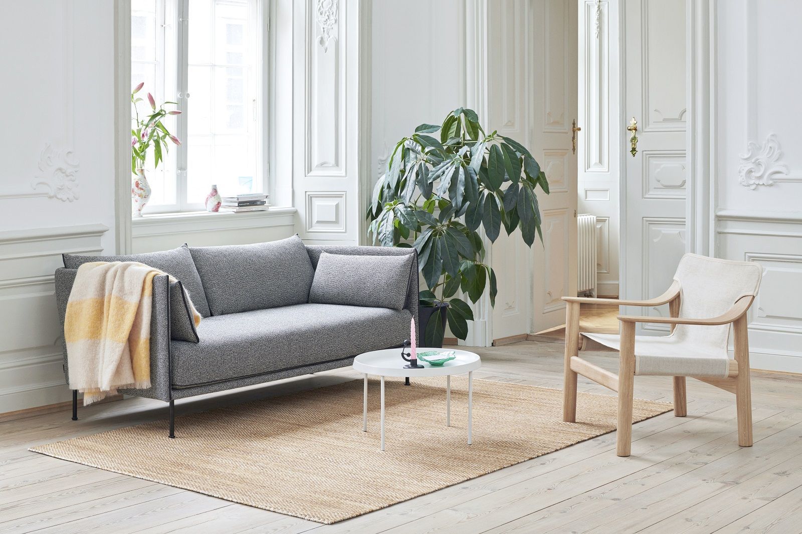 Graues Silhouette Sofa 2-Sitzer Low Hay im Wohnzimmer mit Teppich, Sessel und Zimmerpflanze.