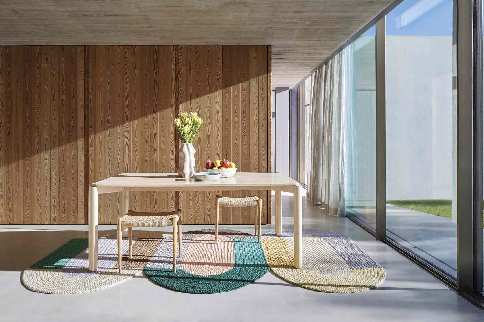 The Crochet Collection Teppich in hellem Wohnraum unter Esstisch mit Stühlen.