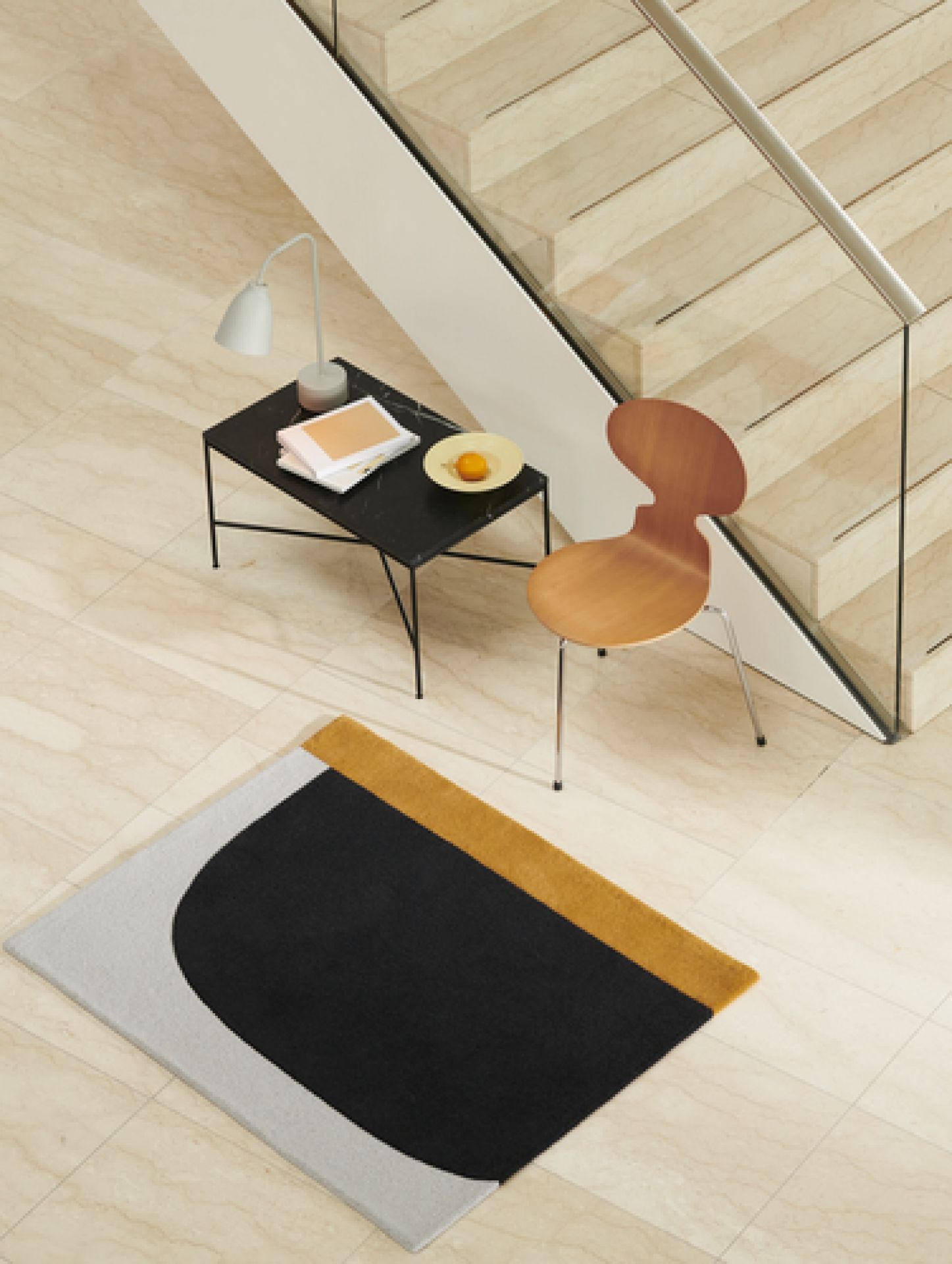 Eleganter Fritz Hansen Planner Couchtisch aus Marmor mit Design-Teppich und Holzstuhl in modernem Wohnraum.