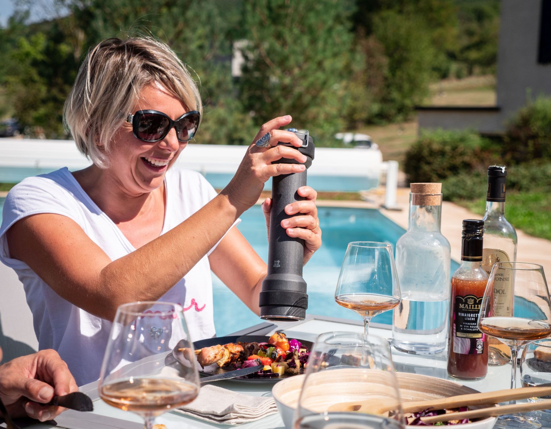 Frau würzt BBQ-Spieß mit Peugeot Pfeffermühle Graphit 30 cm im Freien am Pool.