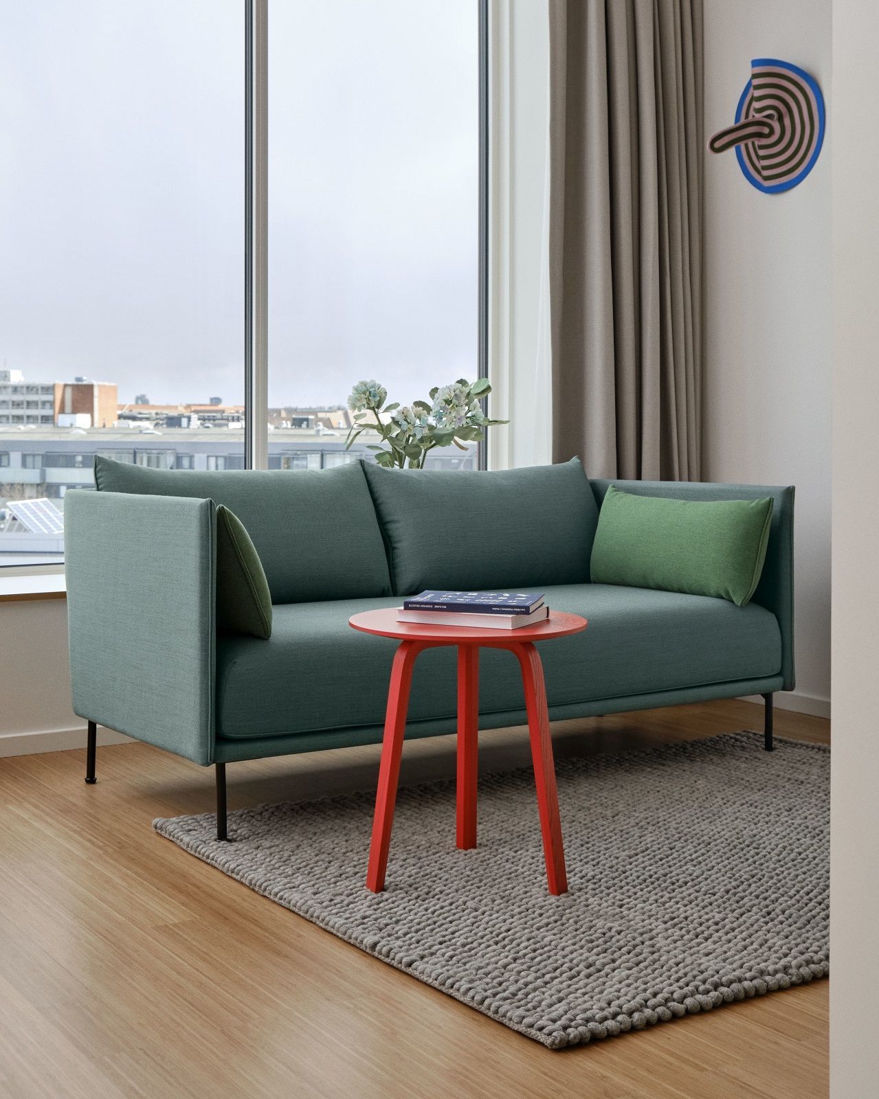 Silhouette Sofa 2-Sitzer Low Hay in Grün mit roten Beistelltisch und Teppich vor Fenster.